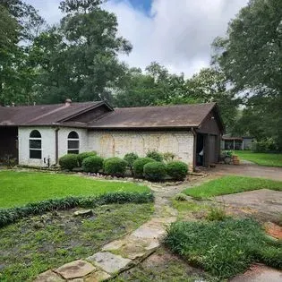 A white house with a brown roof and a stone walkway leading to it.