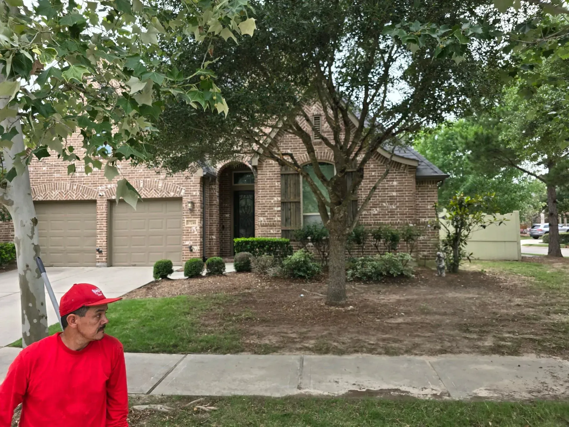 A man in a red hat is standing in front of a house.