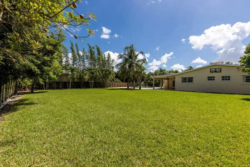 A large lush green field with a house in the background.