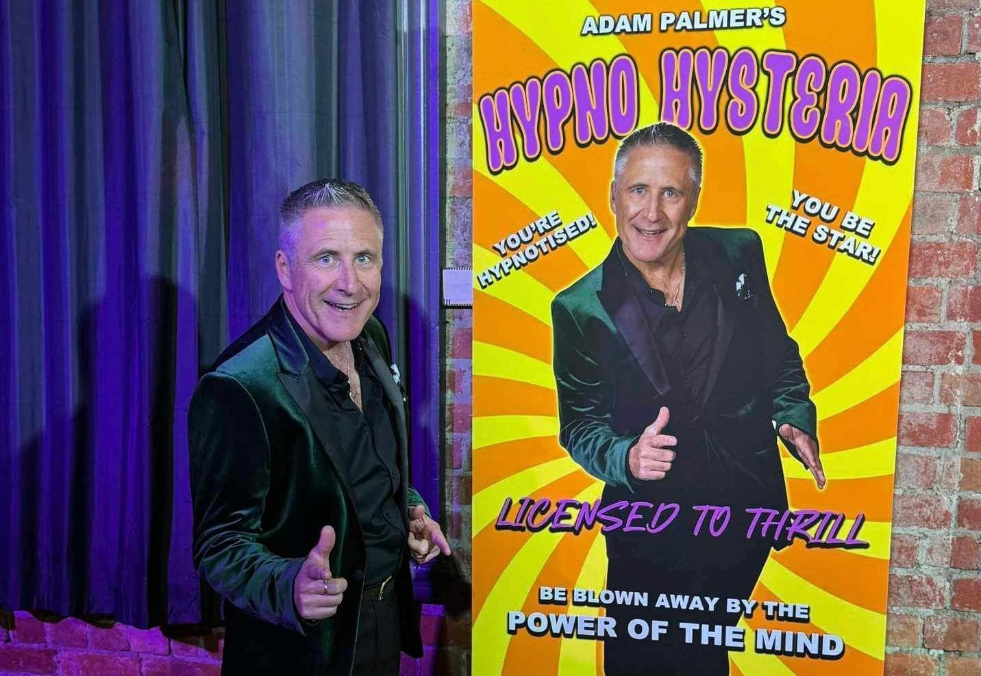 Man in green suit points at the viewer, next to a Hypno Hysteria poster.