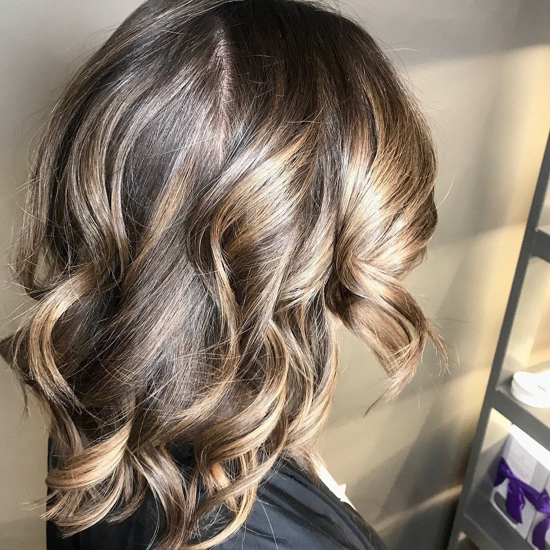 Woman with wavy brown hair, highlighted with lighter brown tones.