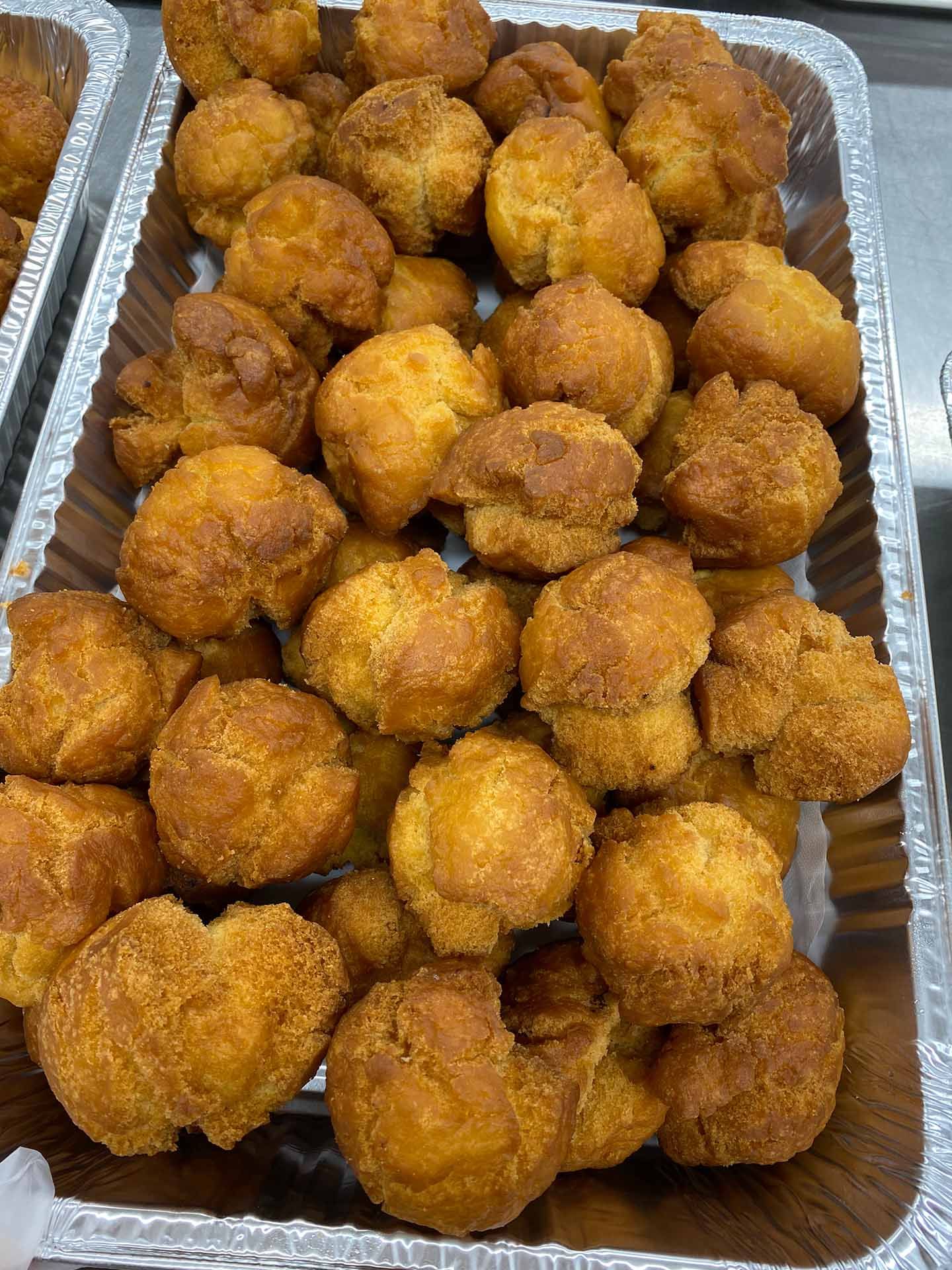 Tray of golden-brown fried dough balls piled in a container