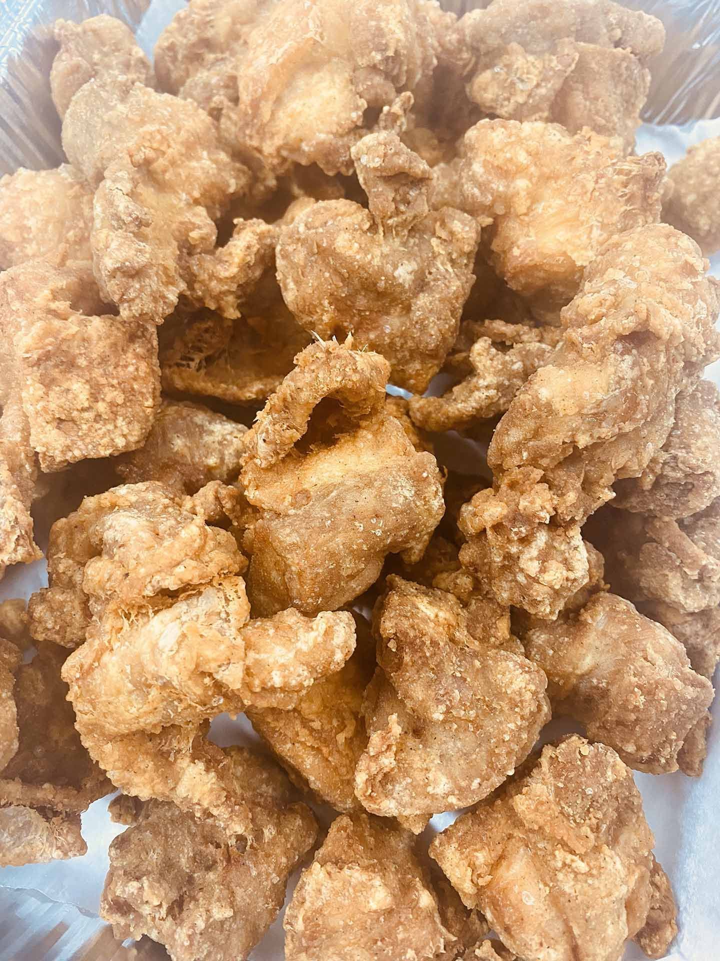 Pile of golden-brown fried chicken pieces in a container