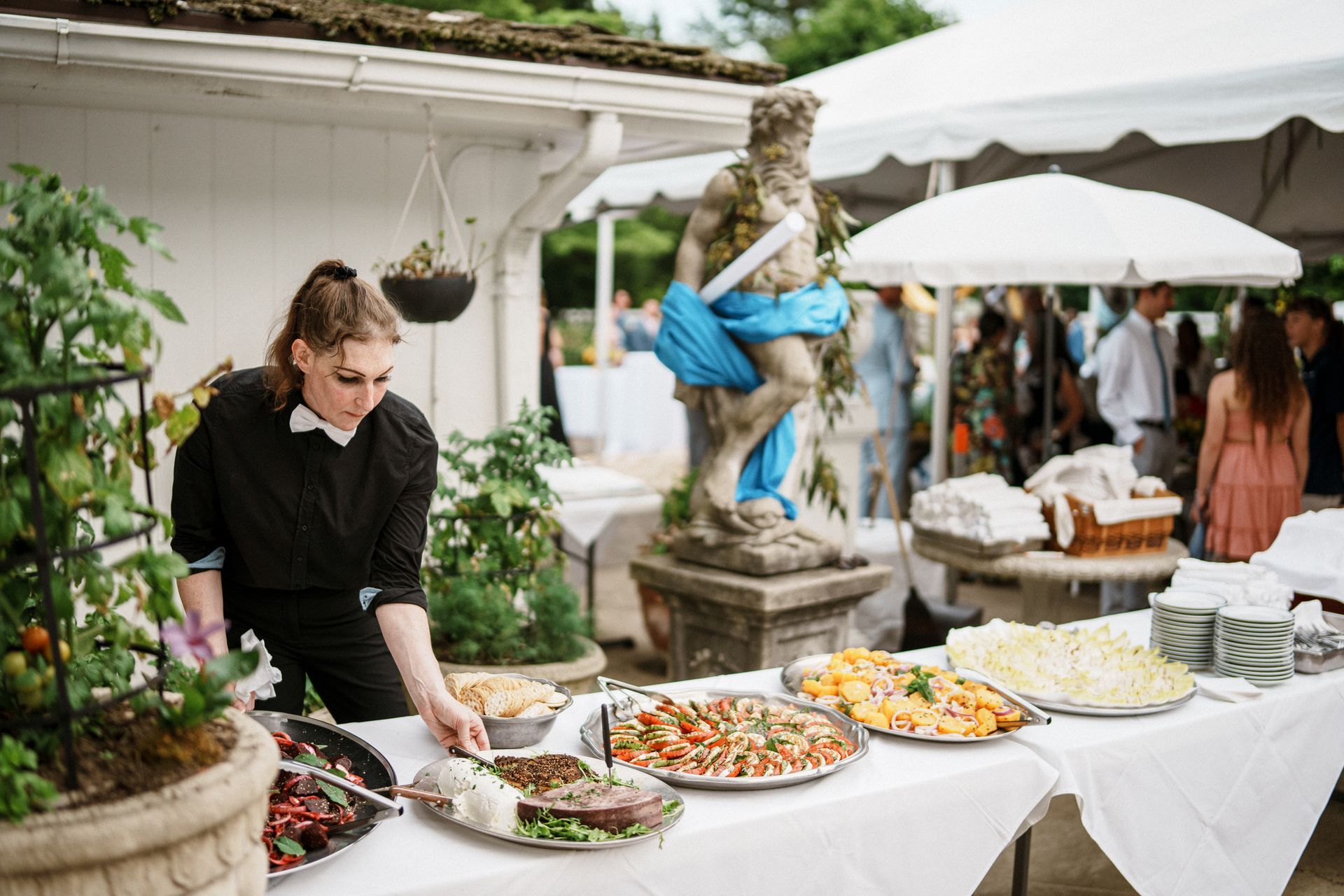 A woman is setting up a table with food for a wedding reception. A woman is setting up a table with food for a wedding reception.