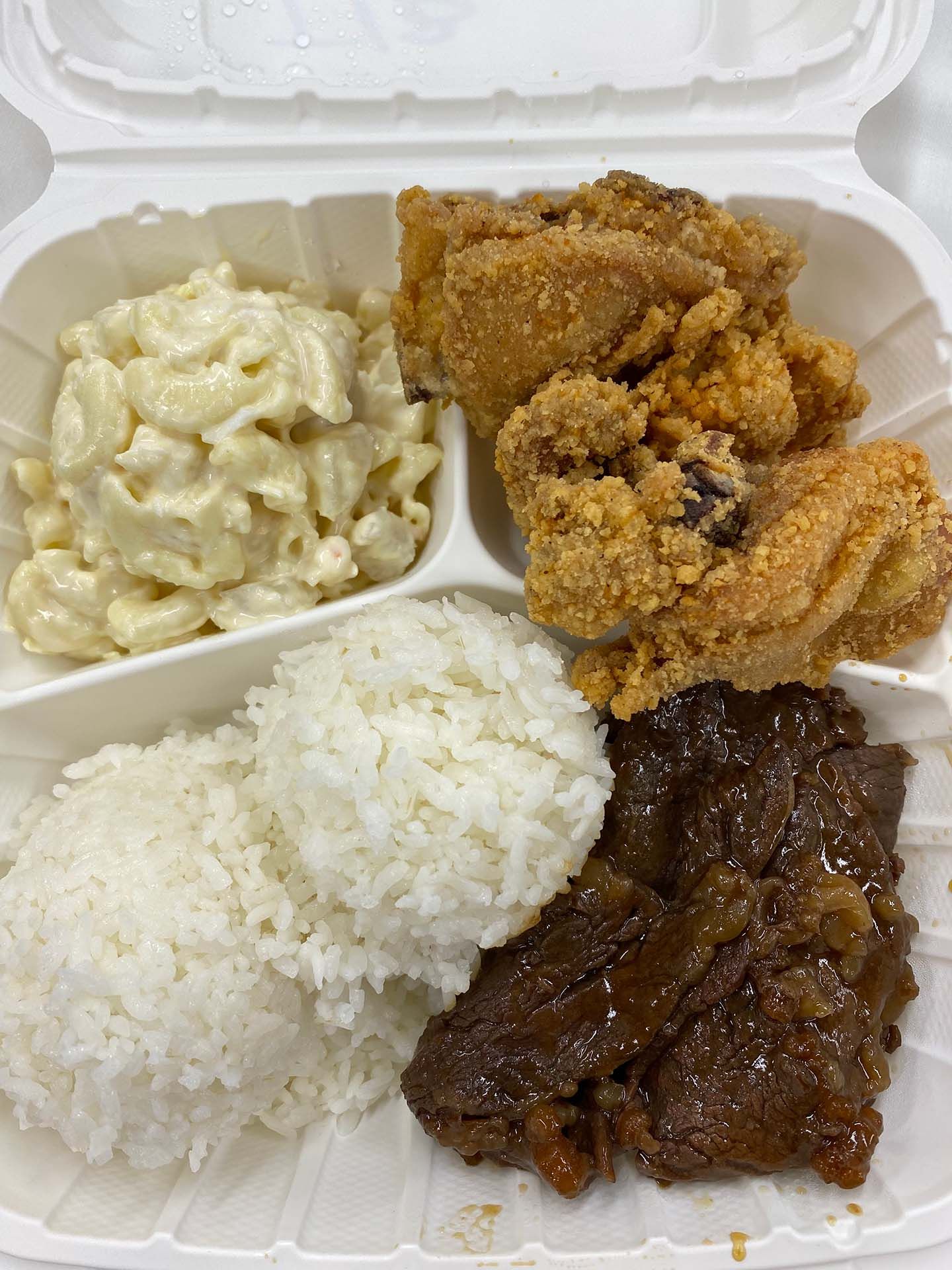 Plate with fried chicken, macaroni salad, rice, and glazed beef