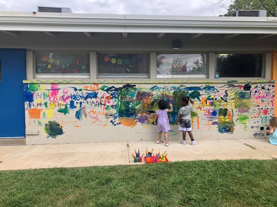 children painting a wall outside