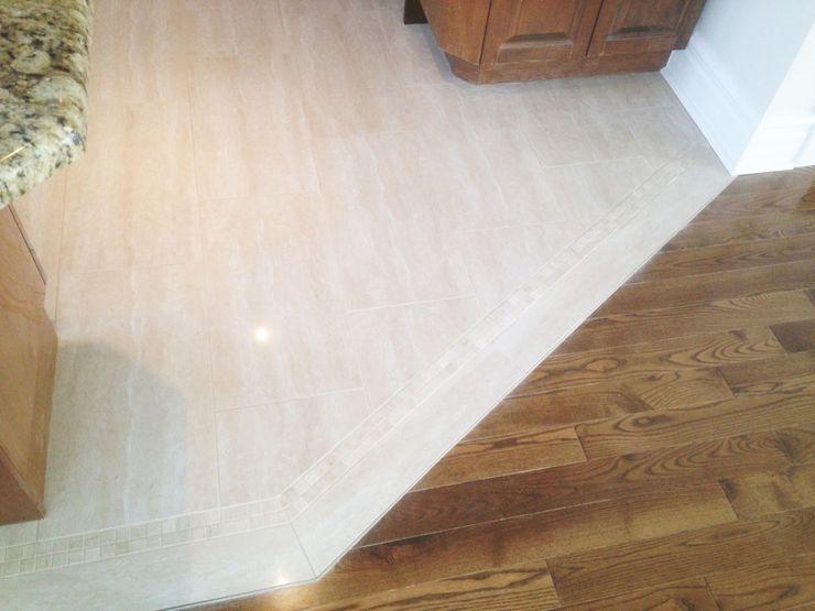 Transition entre un carrelage clair et un parquet foncé, délimitant nettement un bord et un angle.