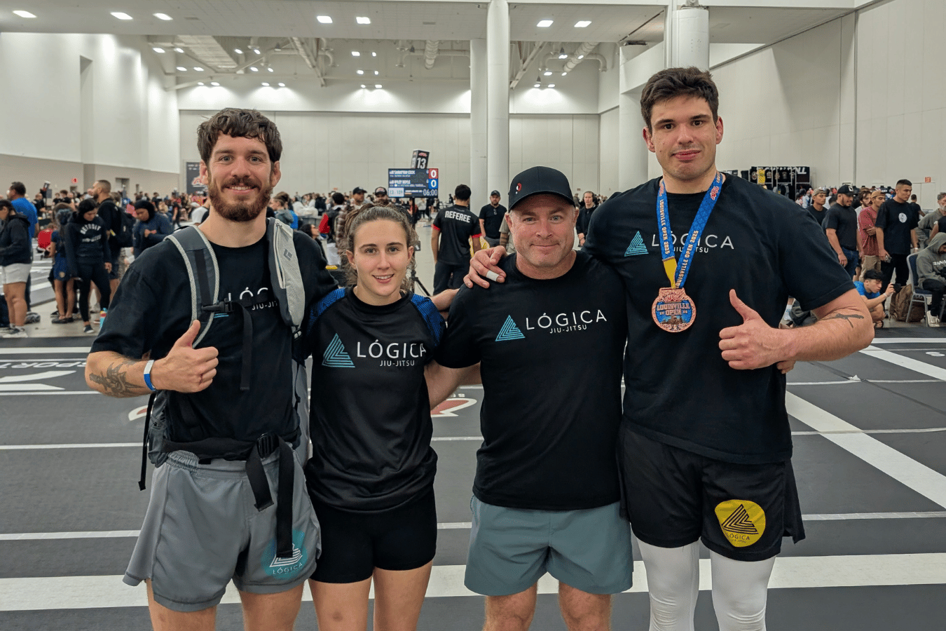 Four Brazilian Jiu-Jitsu teammates smiling after a tournament, wearing medals.