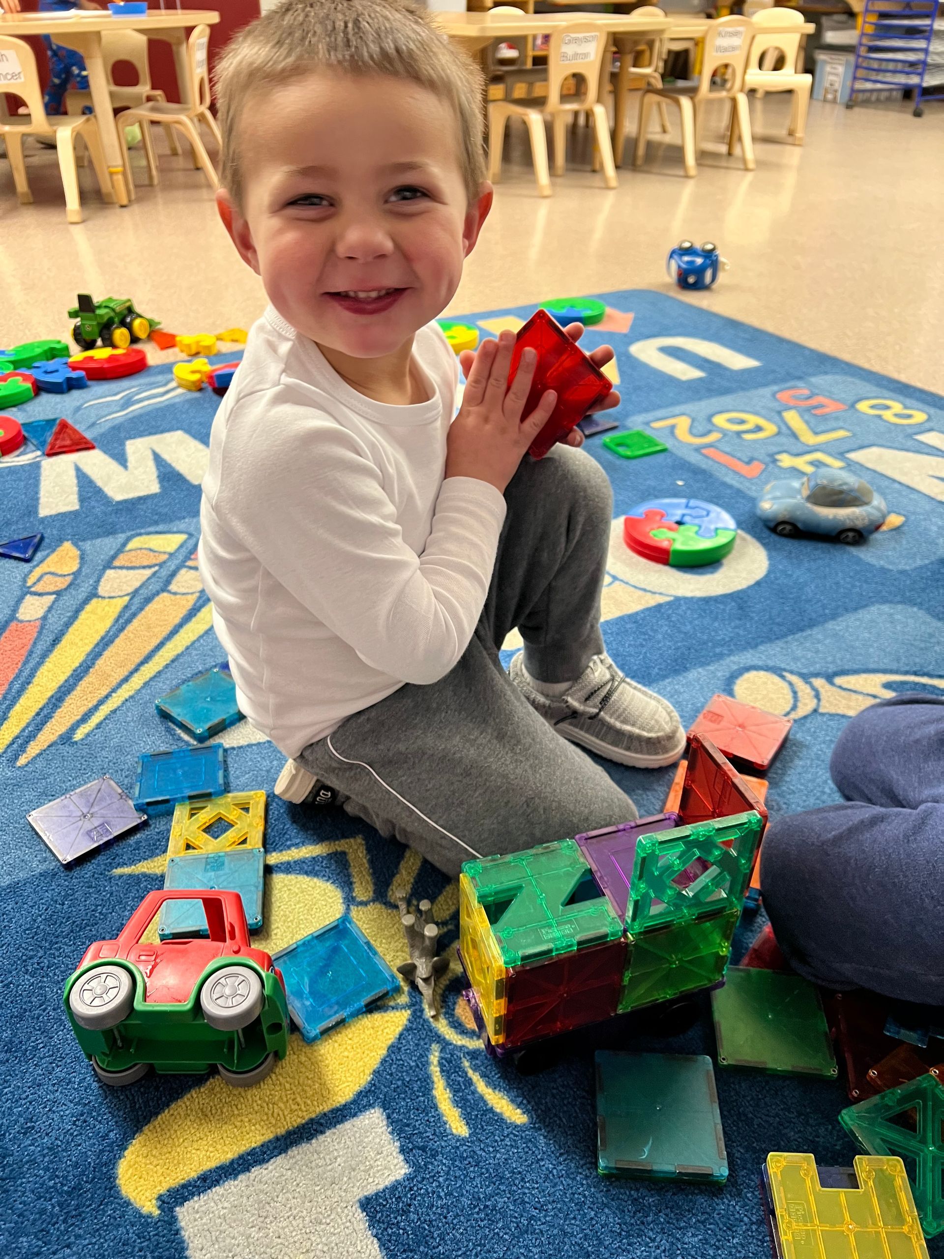 A young boy is sitting on the floor playing with toys.