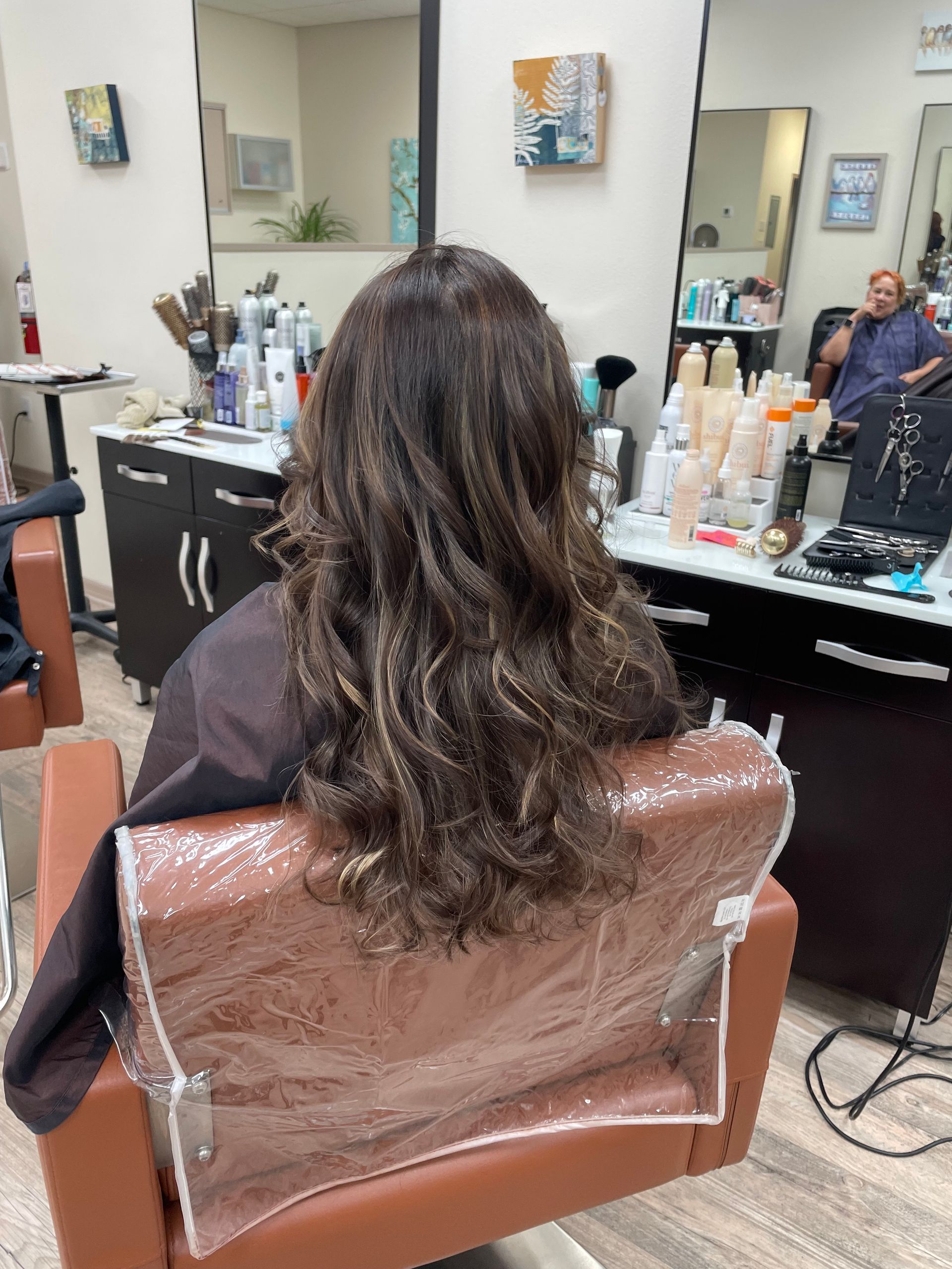 A woman is sitting in a chair at a hair salon.