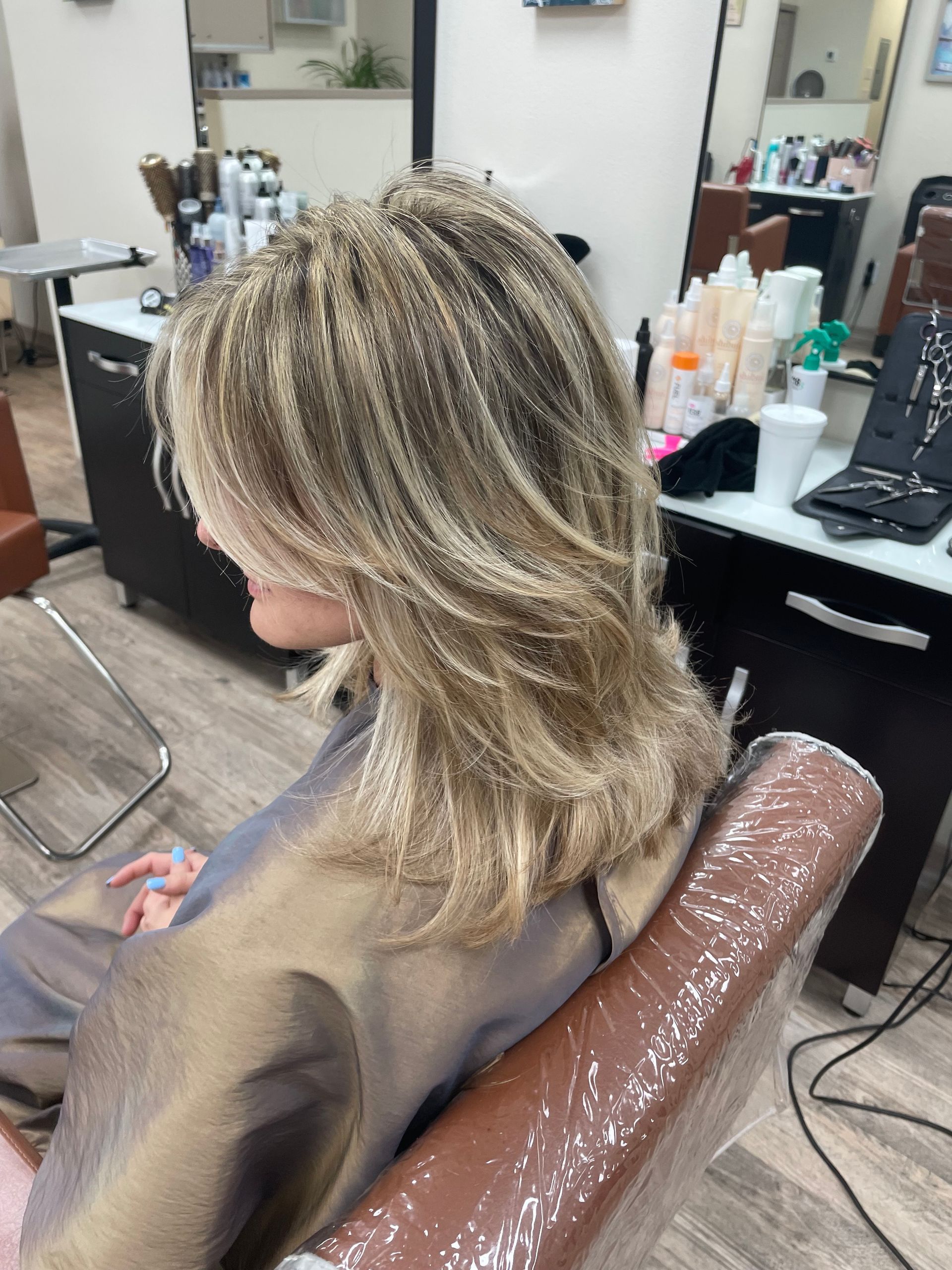 A woman with blonde hair is sitting in a chair in a salon.