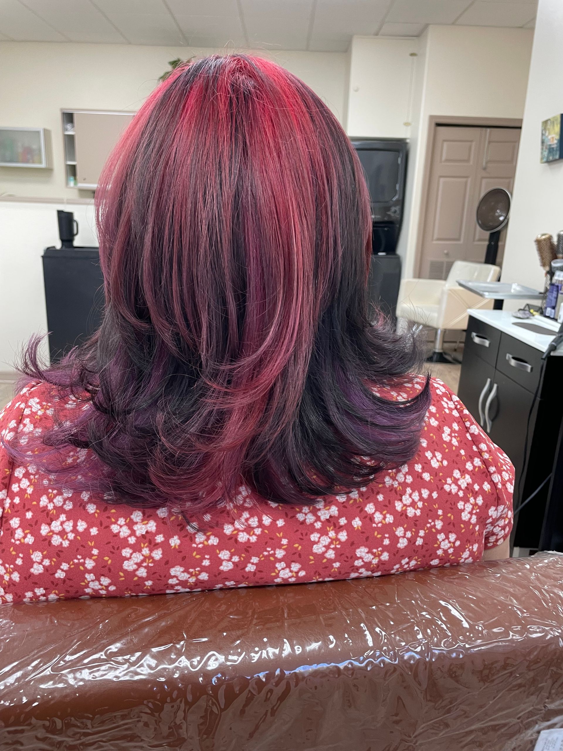 A woman with red hair is sitting in a chair in a salon.