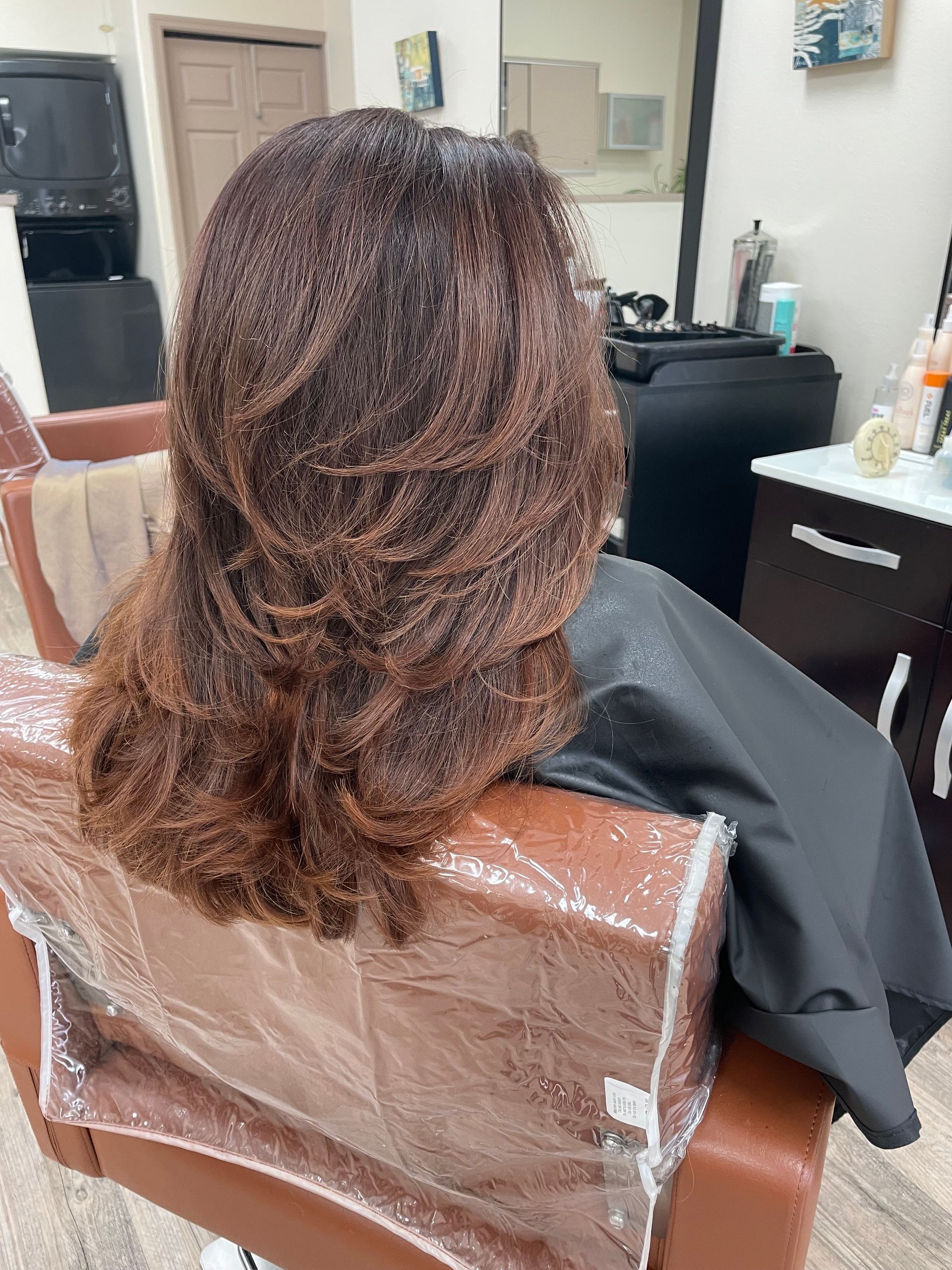 A woman is sitting in a chair with her hair in a salon.