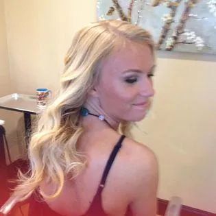 A woman with long blonde hair is sitting in a chair in front of a table