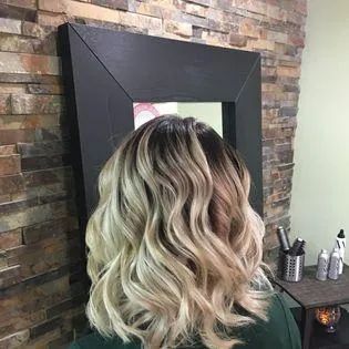 A woman with blonde hair is standing in front of a mirror