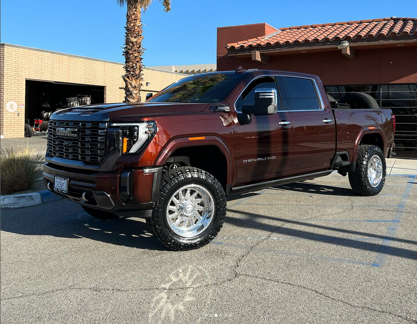 A red pickup truck is parked in a parking lot in front of a building.