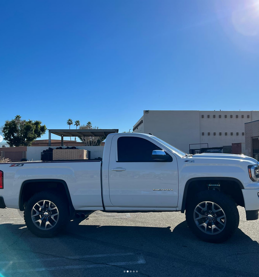 A white truck is parked in a parking lot in front of a building