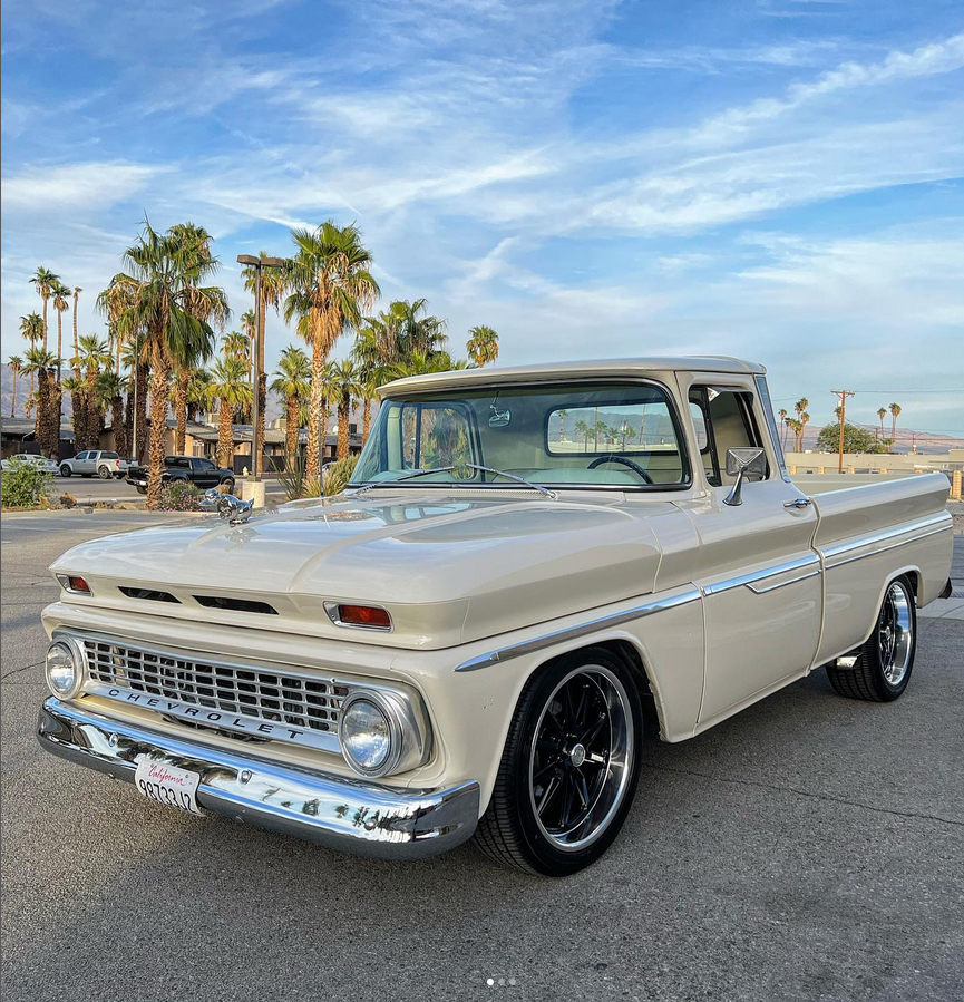 A white truck is parked in a parking lot with palm trees in the background.
