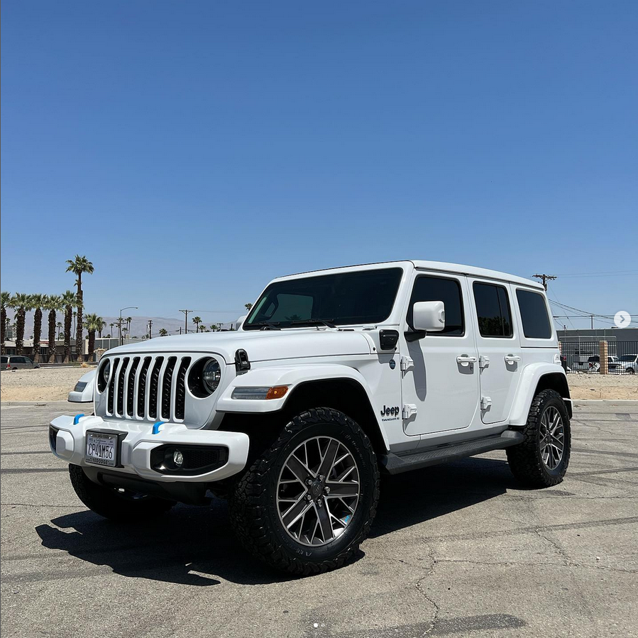 A white jeep wrangler is parked in a parking lot on a sunny day.