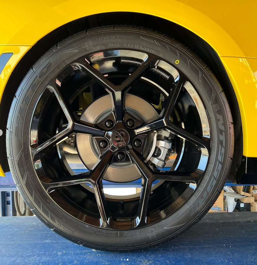 A close up of a yellow car with black wheels and tires