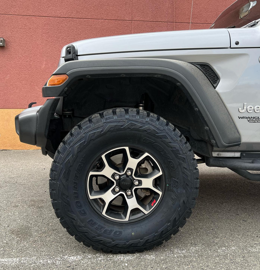 A silver jeep is parked in front of a building