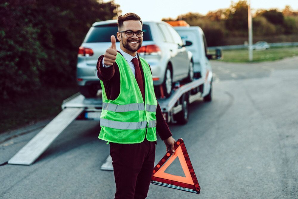 A Man Is Giving A Thumbs Up In Front Of A Tow Truck — Tonics Automotive in Garbutt, QLD