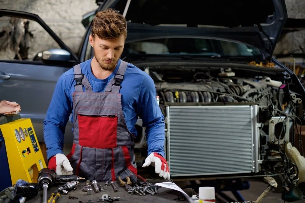 A Man Is Working On The Radiator Of A Car In A Garage — Tonics Automotive in Garbutt, QLD