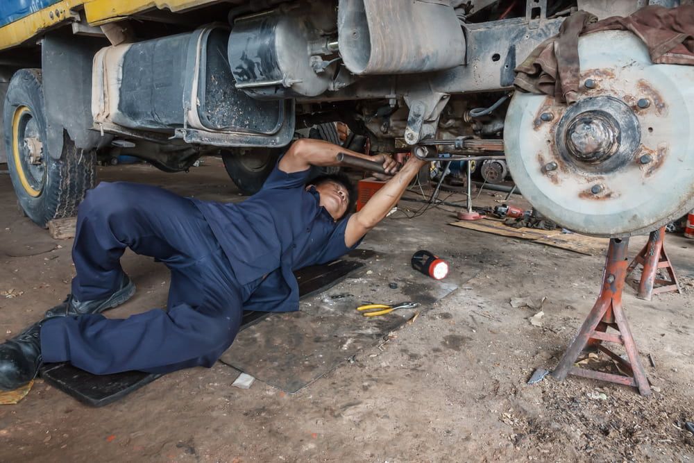 A Man Is Working On A Truck In A Garage — Tonics Automotive in Garbutt, QLD