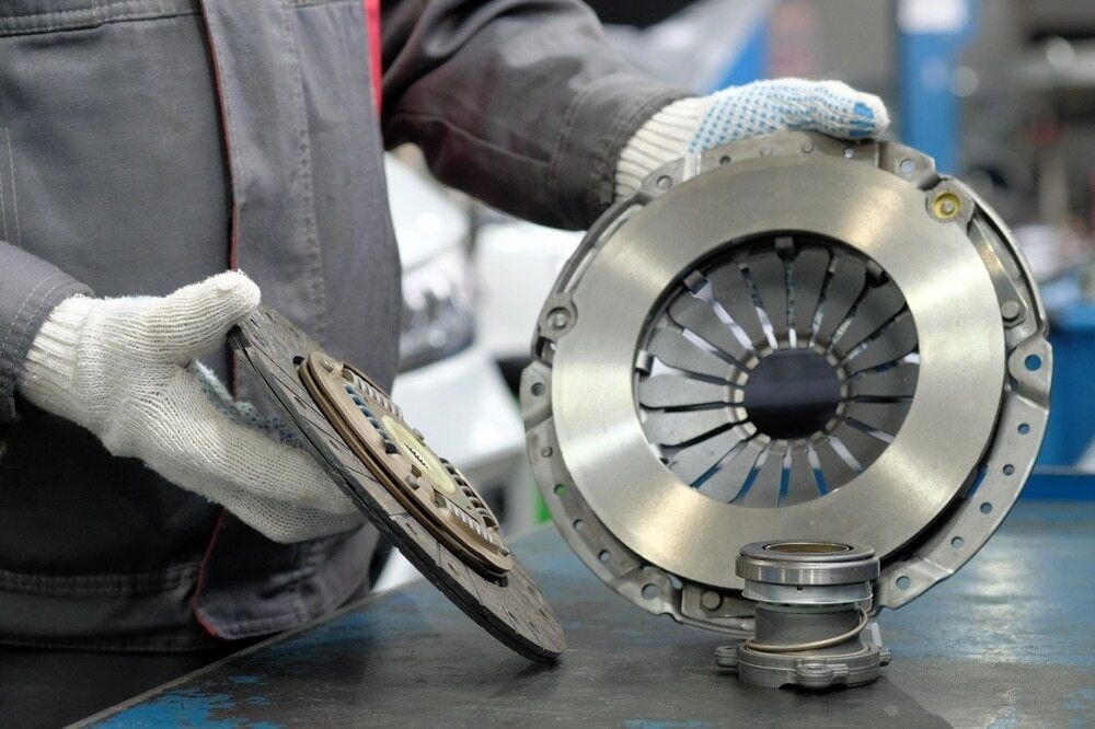 A Man Is Holding A Clutch Plate In His Hands — Tonics Automotive in Garbutt, QLD