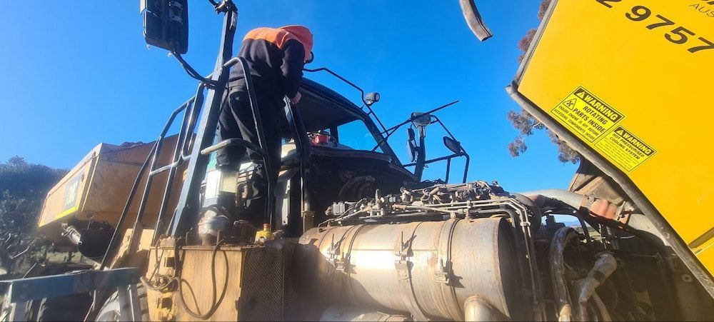 A Man is Standing on Top of a Yellow Truck — MJR Auto Glass In Canberra, ACT