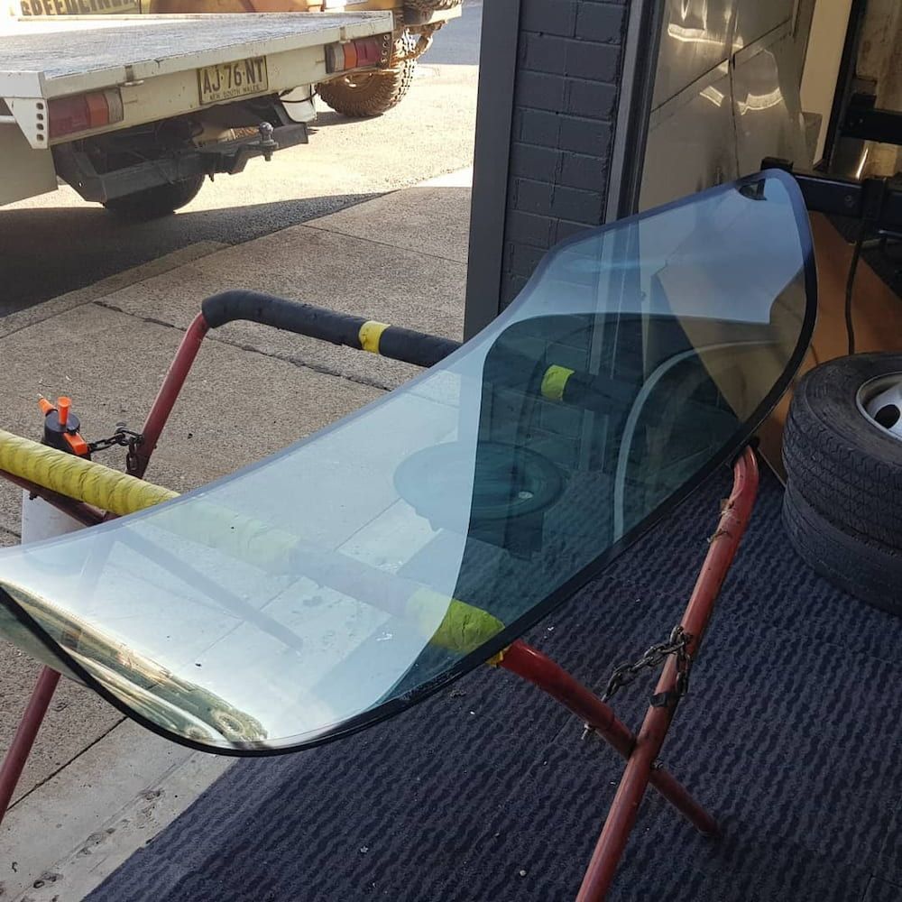 A Windshield is Sitting on a Stand in Front of a Truck — MJR Auto Glass In Crookwell, NSW