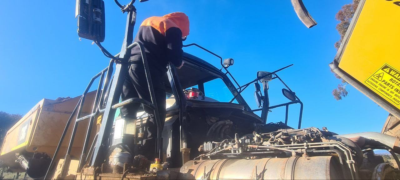 A Man Is Standing On Top Of A Construction Vehicle — MJR Auto Glass In Goulburn, NSW