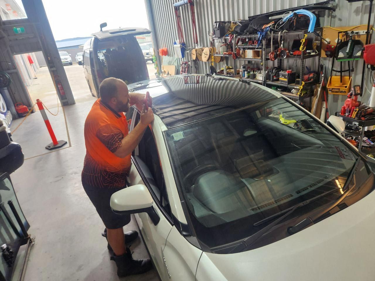 A Man Is Working On A Car In A Garage — MJR Auto Glass In Goulburn, NSW