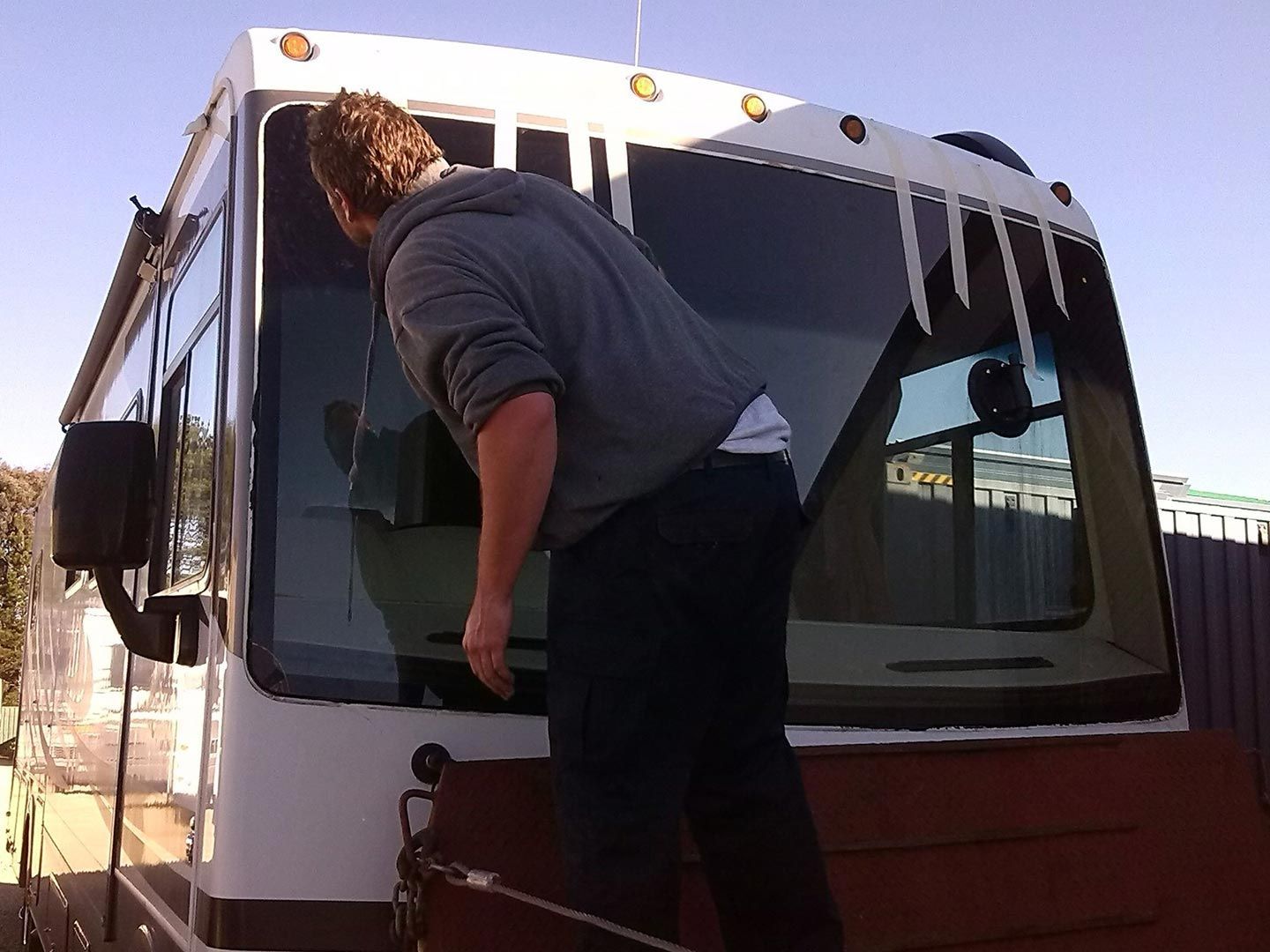 A Man Standing In Front Of A Bus With Icicles On The Windshield — MJR Auto Glass In Goulburn, NSW
