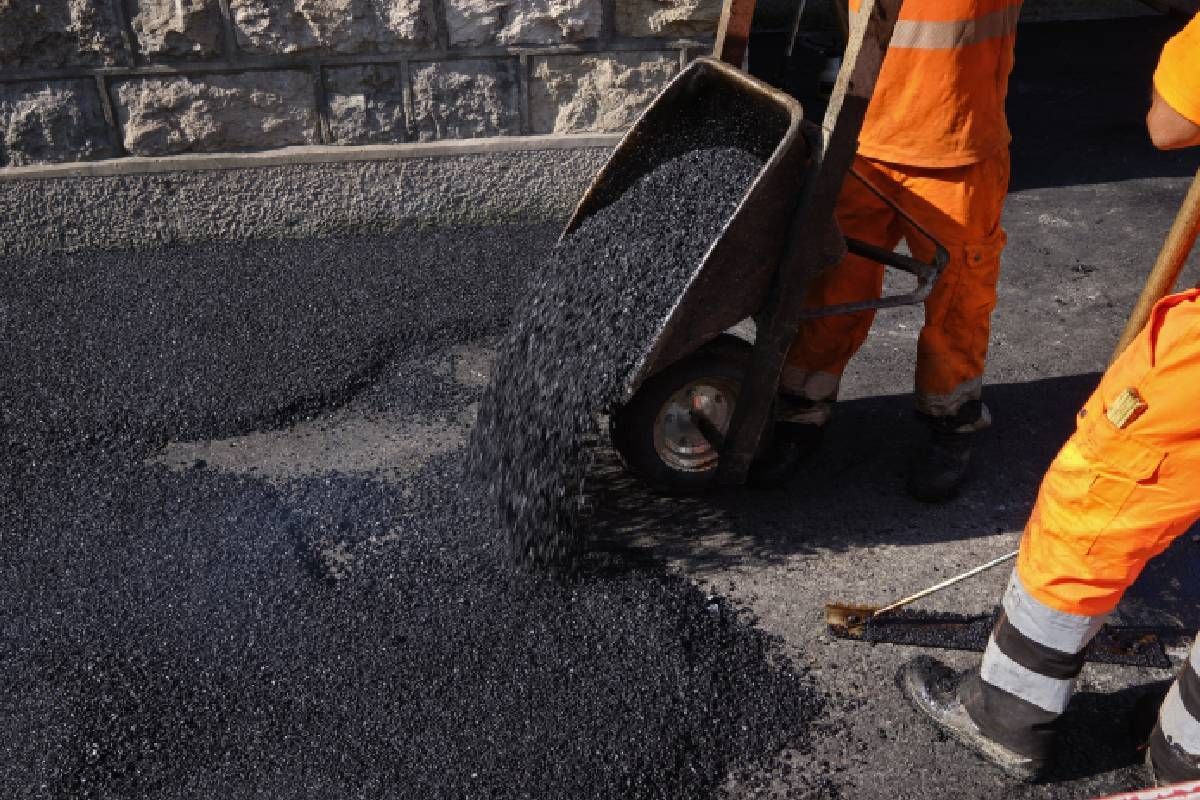 Two people pouring fresh asphalt to recoat a driveway near Lexington, Kentucky (KY)