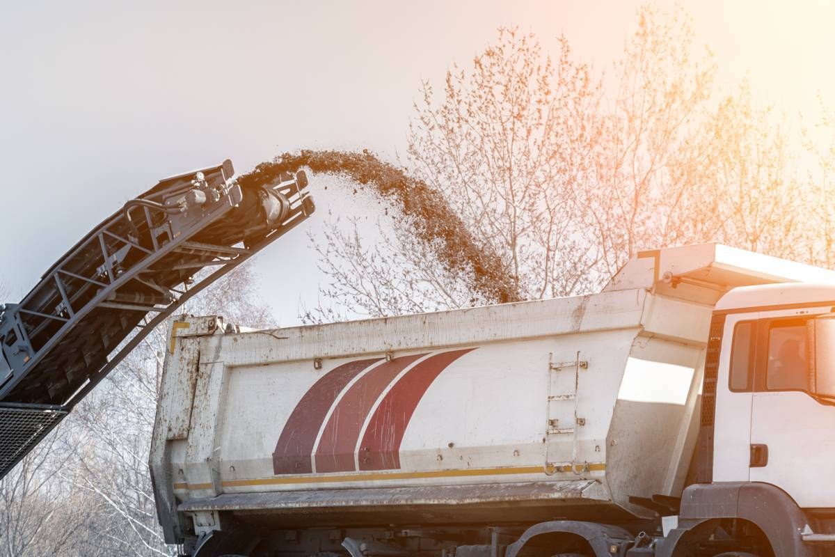 A milling machine throwing asphalt to a truck for recycling near Lexington, Kentucky (KY)