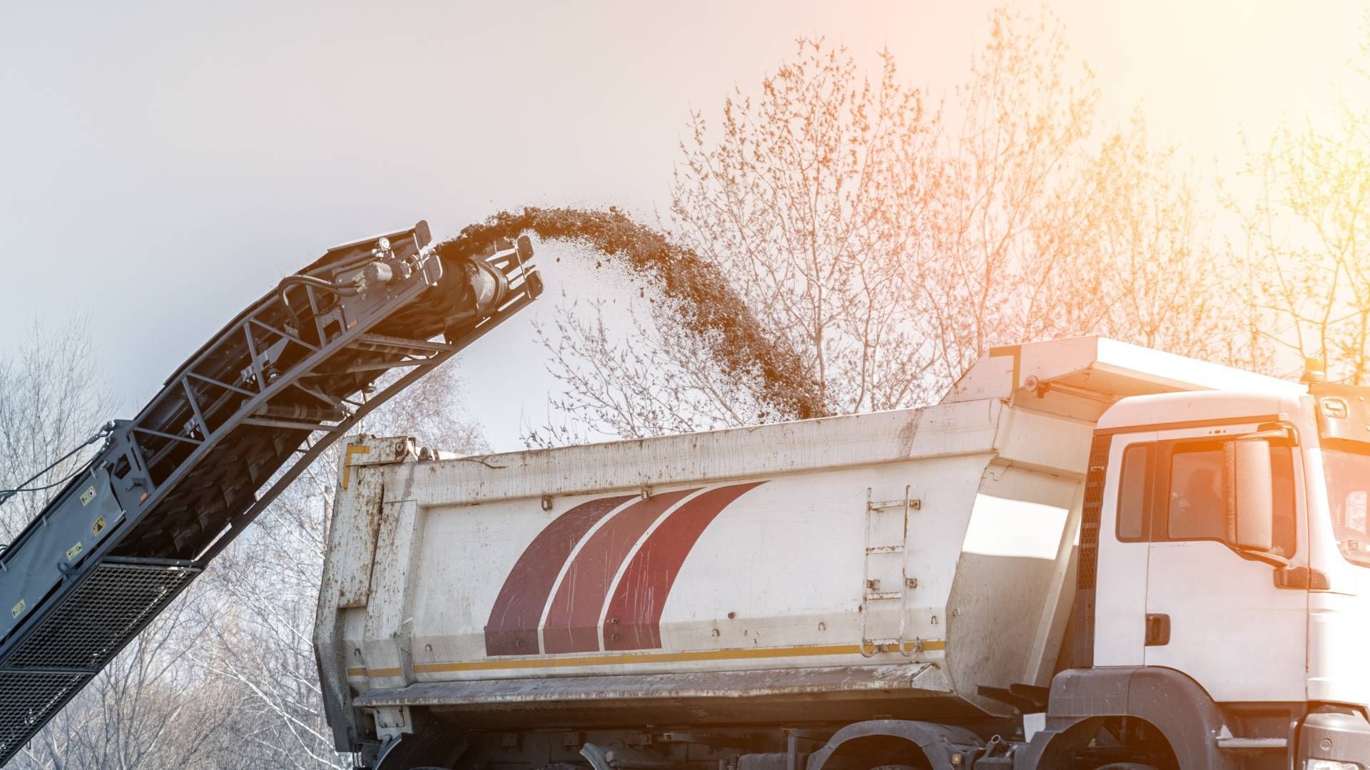 A milling machine throwing asphalt to a truck for recycling near Lexington, Kentucky (KY)