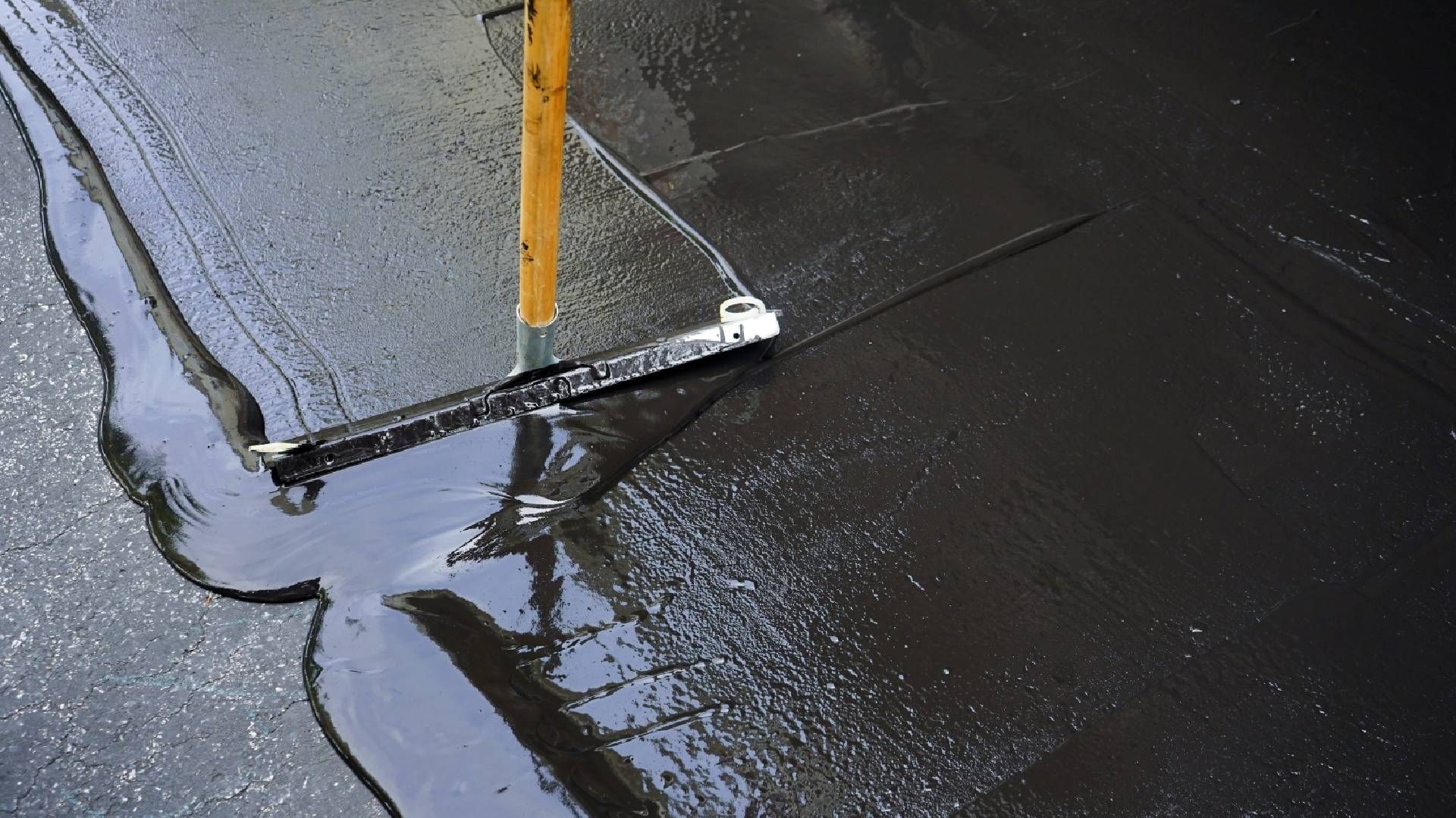 Someone using a squeegee to complete an asphalt seal coating near Richmond, Kentucky (KY)