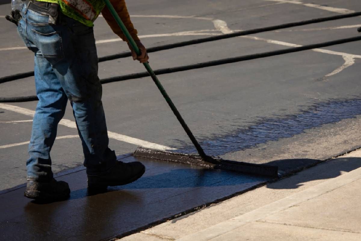 Worker using a sealcoating brush during asphalt resurfacing project near Richmond and Lexington, Kentucky (KY)