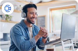 Um homem usando fones de ouvido está sentado em frente a um laptop.