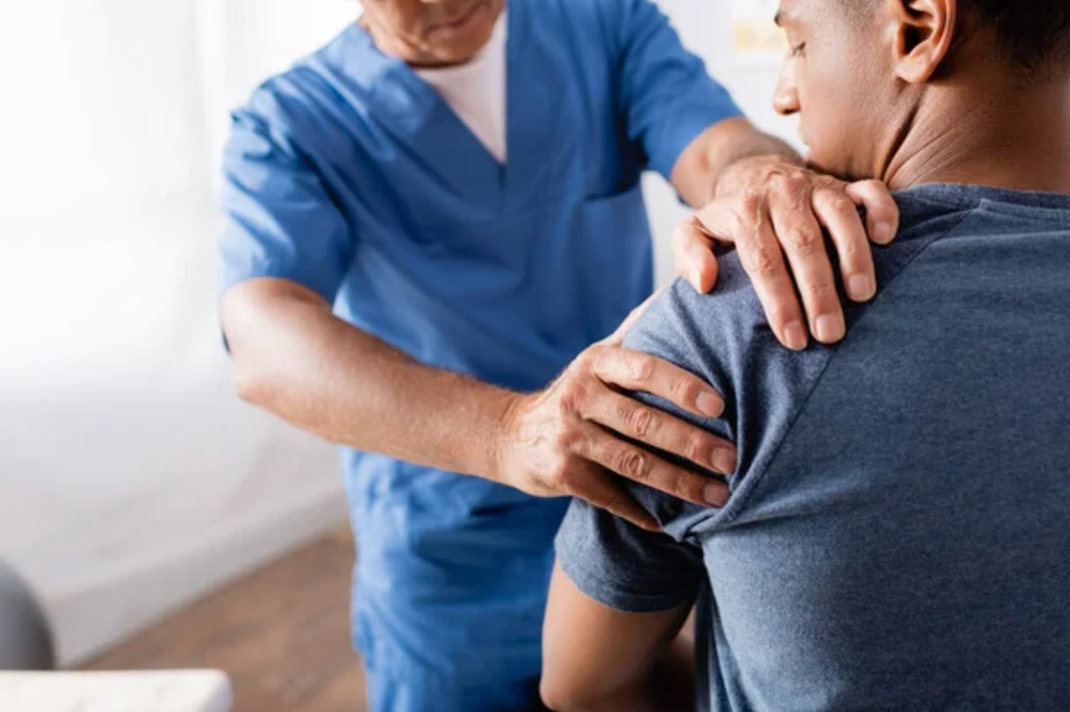 Um médico está examinando o ombro de um paciente em um hospital.