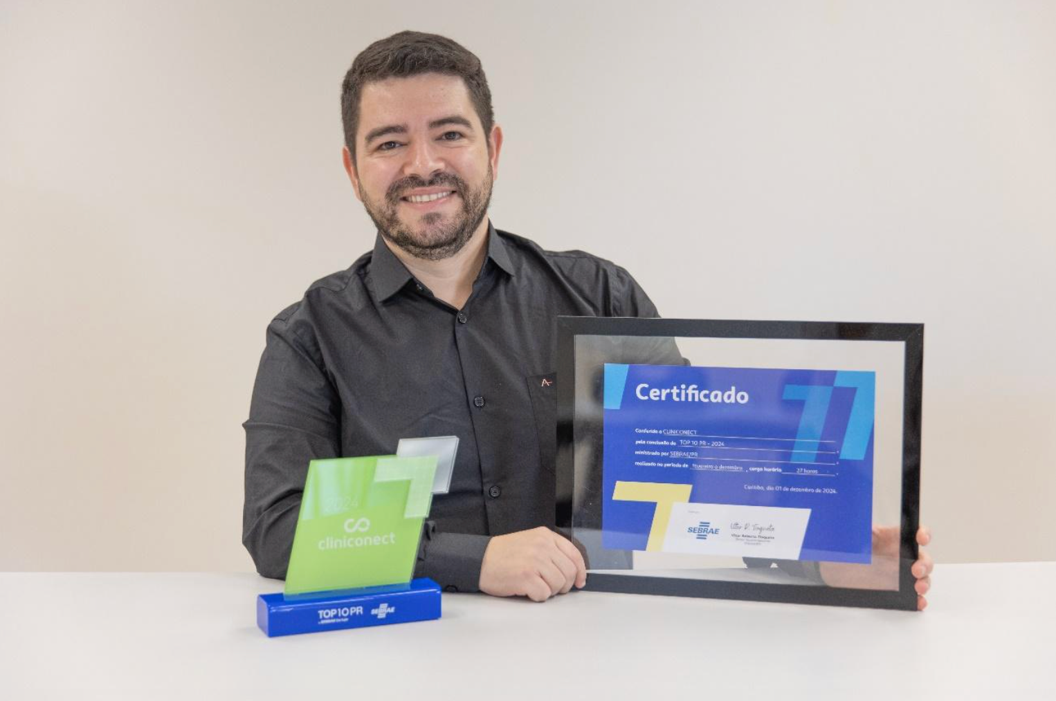 Um homem está segurando um certificado emoldurado e um troféu.