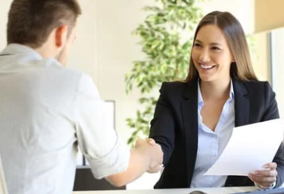 A woman is shaking hands with a man during a job interview.