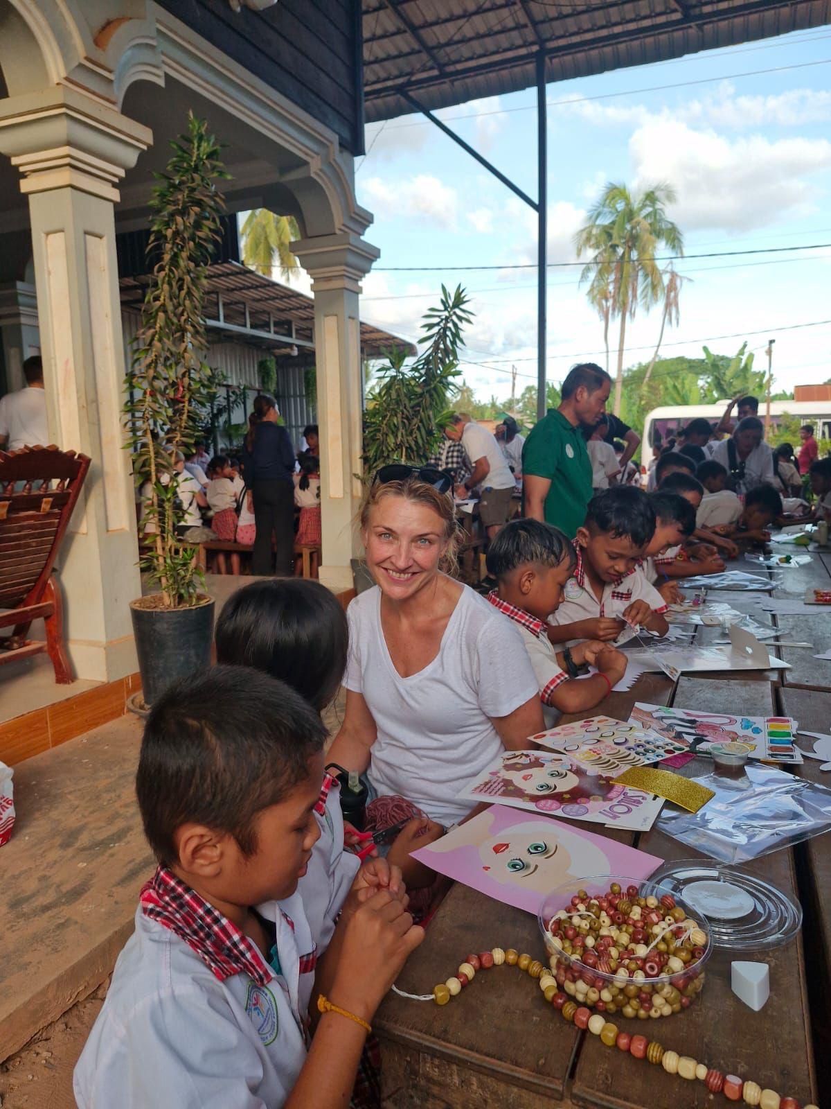 A woman is sitting at a table with a group of children.