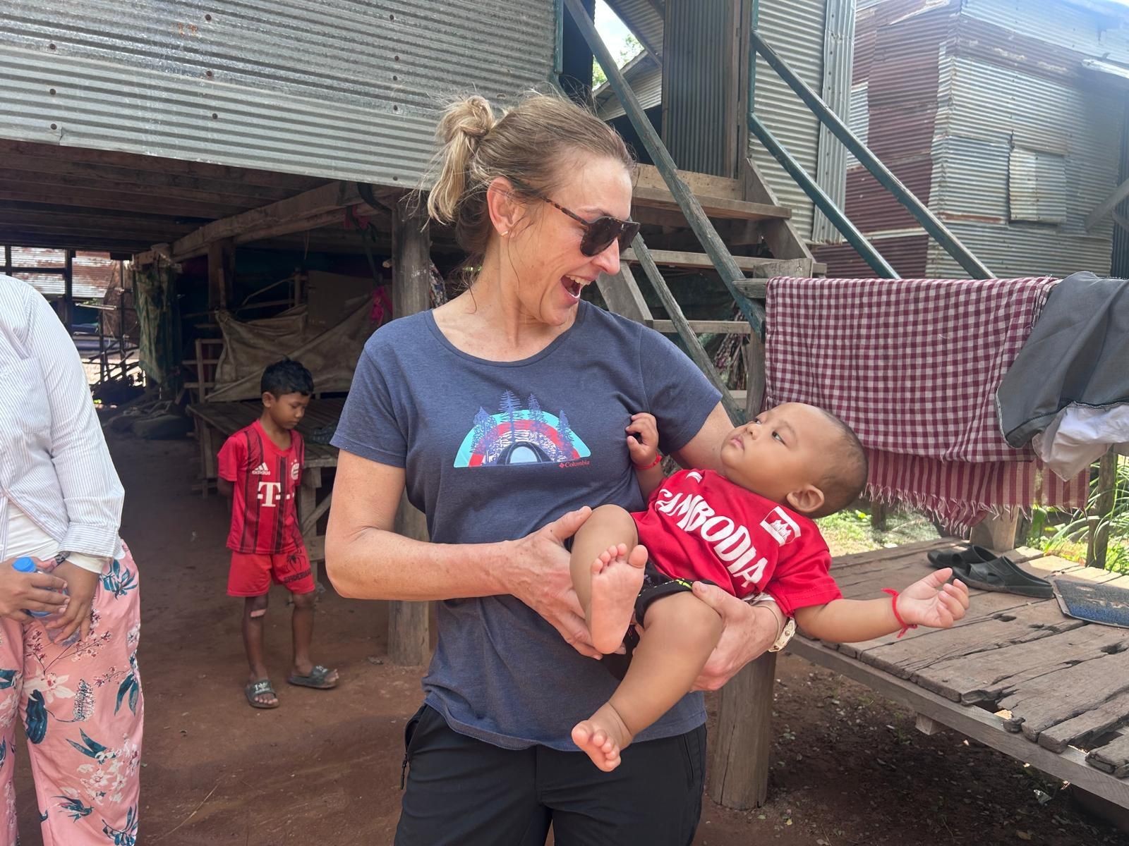 A woman is holding a baby in her arms in front of a building.