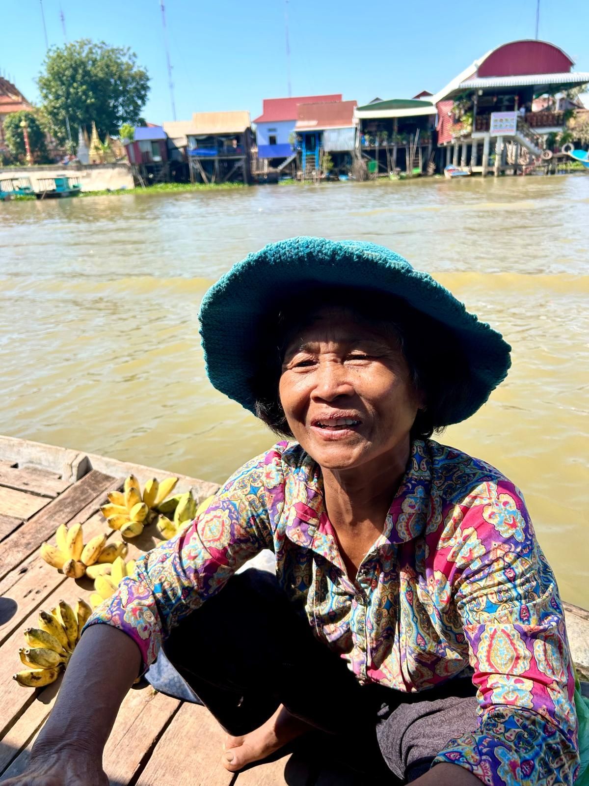 Woman washing dishes outside her home. Child looks on. Tropical setting.