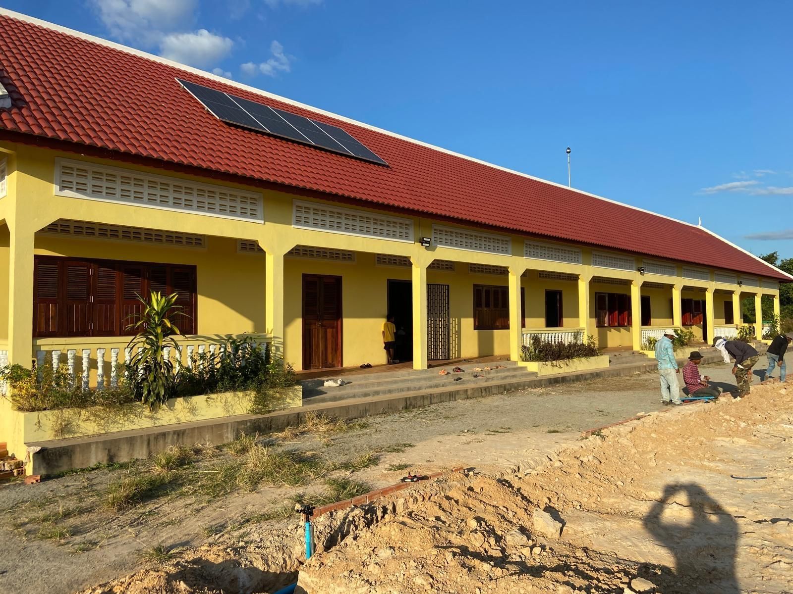 Children play in a cluttered, open-air shelter; one swings, others watch.