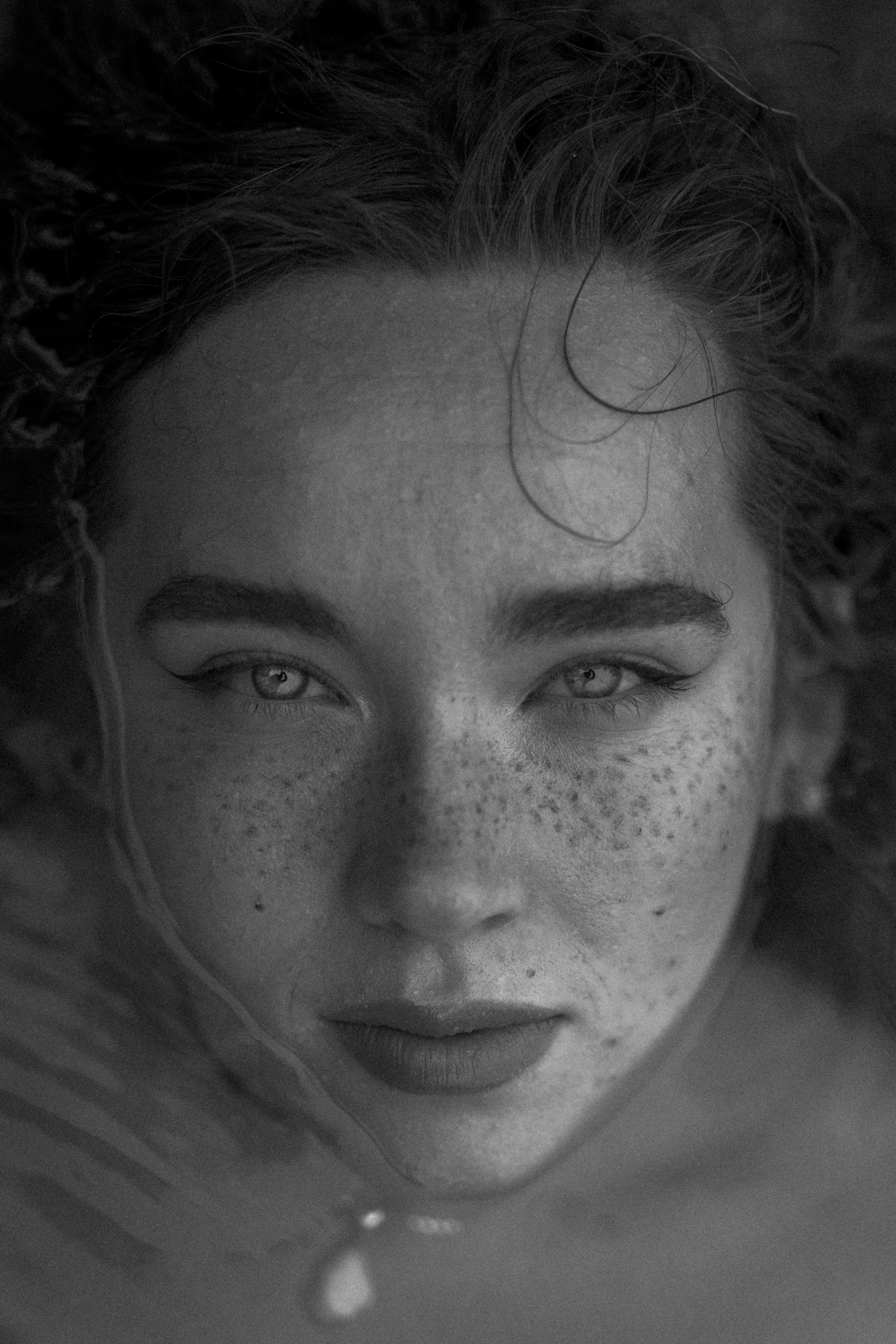 A close up of a woman 's face with freckles in a black and white photo.