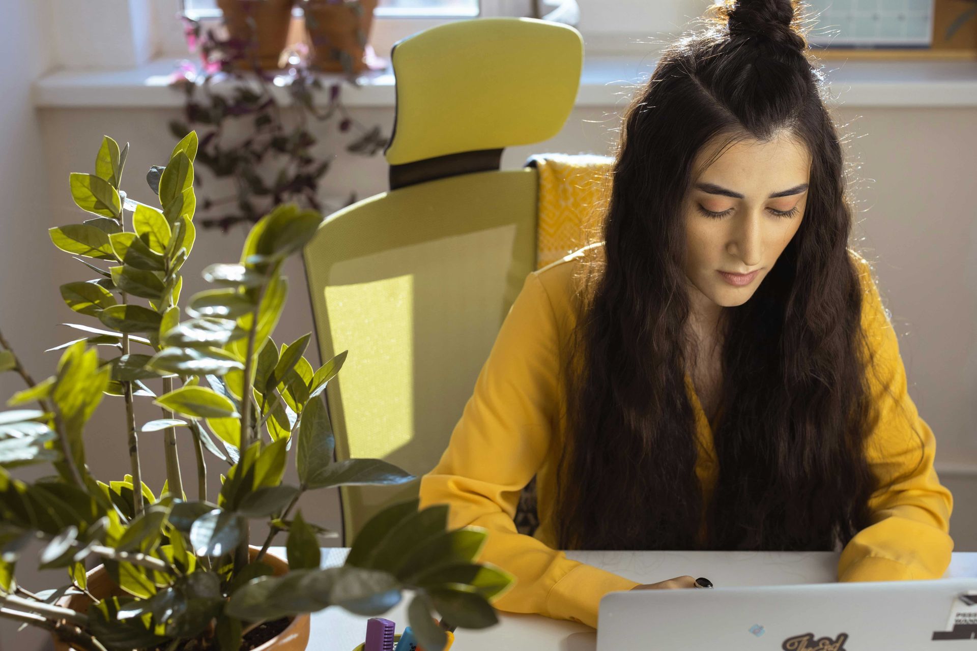 A woman with a towel wrapped around her head is talking on a cell phone while holding a piece of paper.