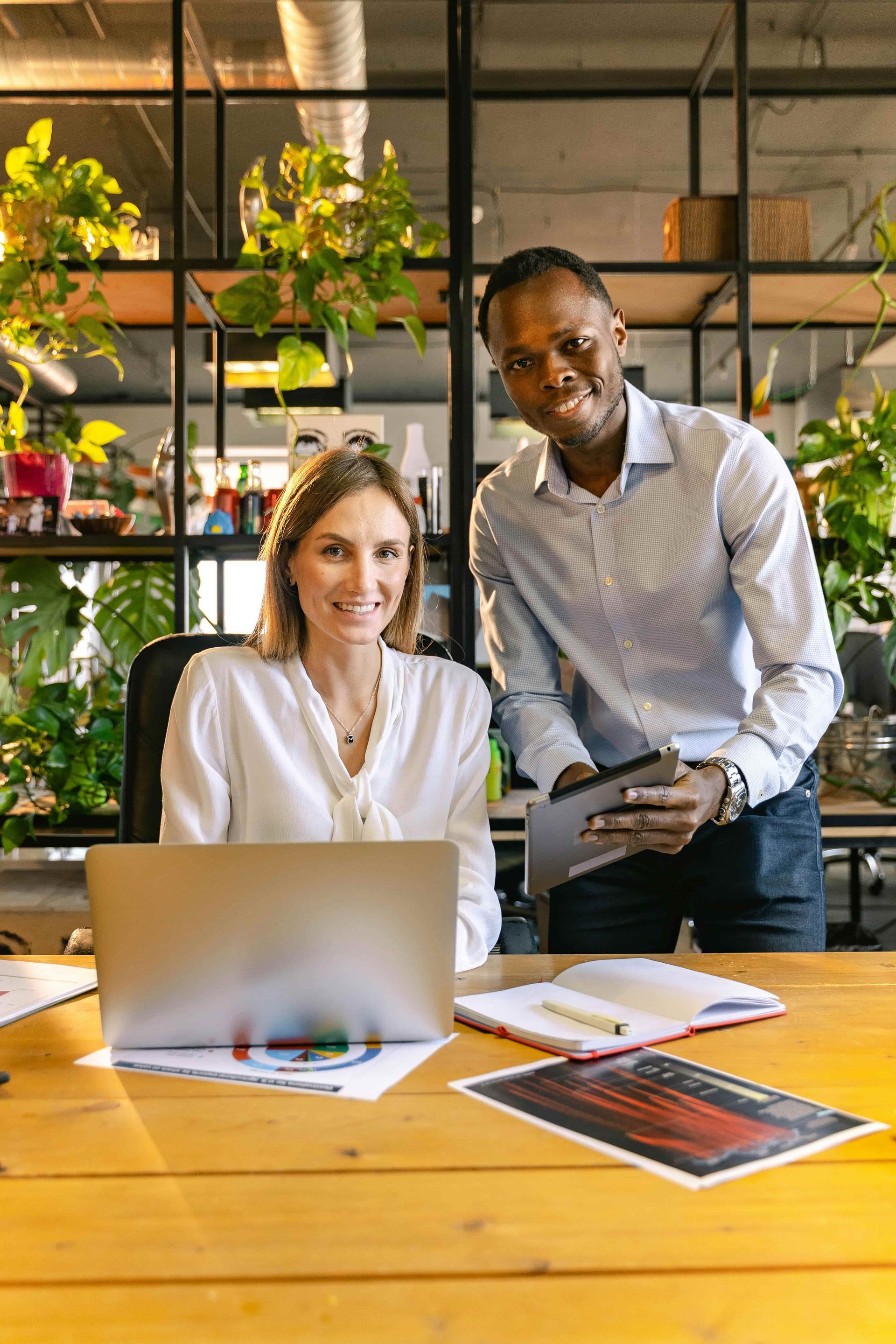 A man and a woman are standing next to each other in front of a laptop computer.